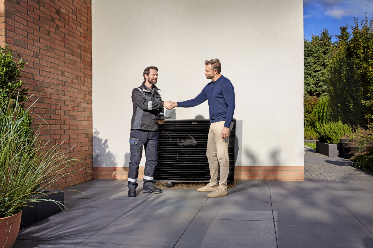 Установщик пожимает руку клиенту перед наружным блоком Daikin Altherma