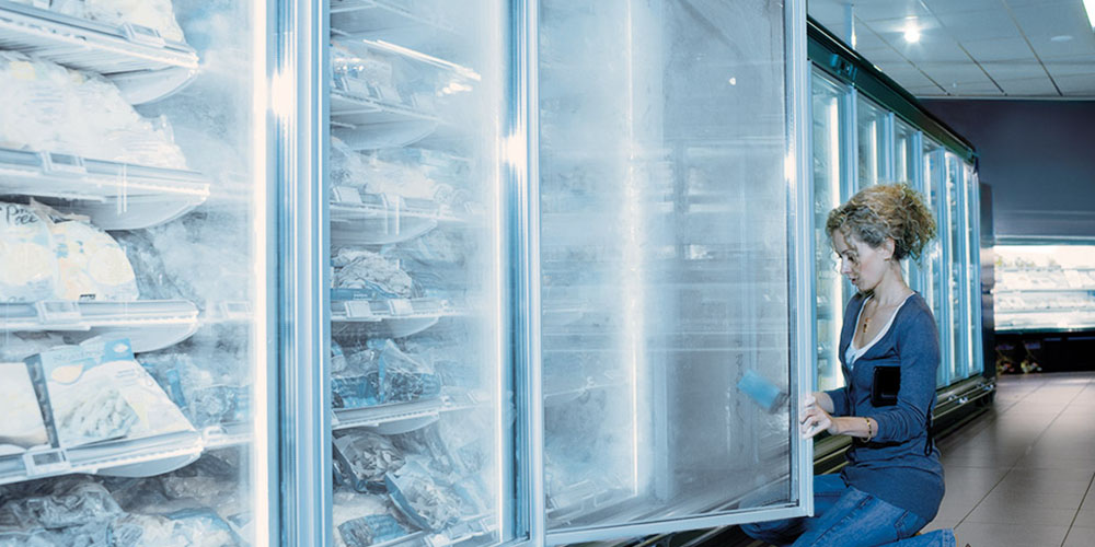 Женщина чистит морозильники в продуктовом магазине