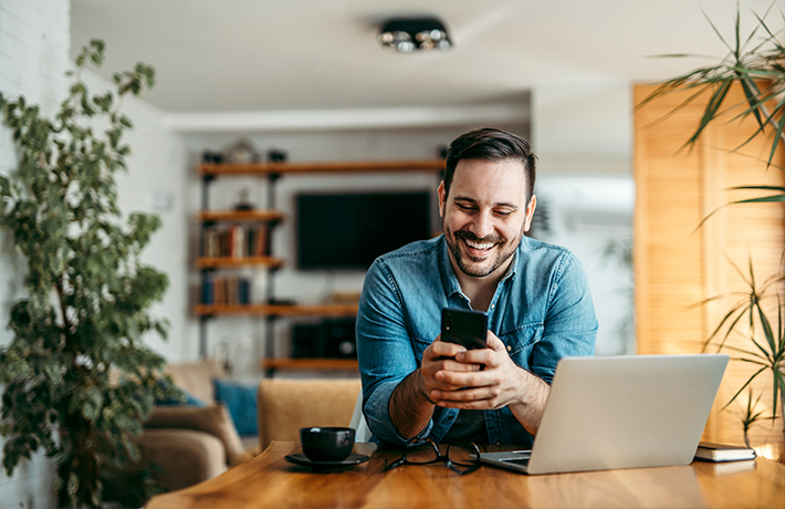 Мужчина смотрит на экран своего мобильного телефона у себя дома